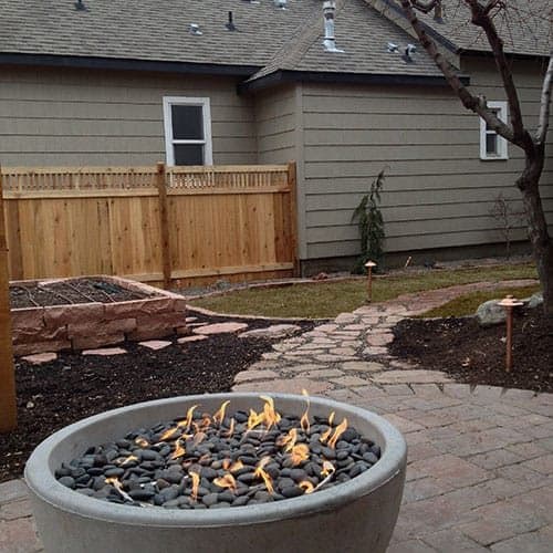 Stone fire pit and paver seating area in a Treasure Valley backyard