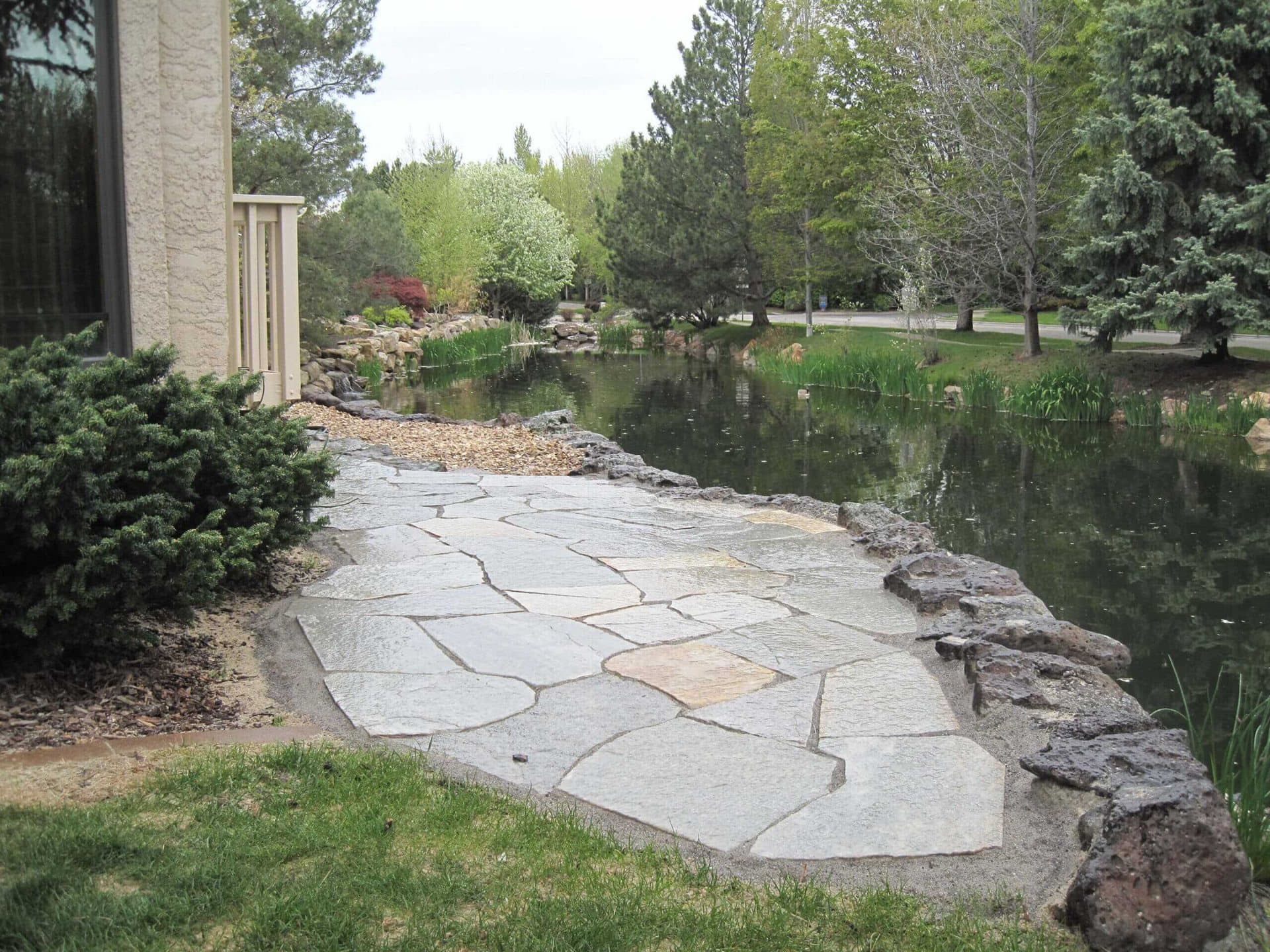 Custom paver patio with a water feature and lush landscaping in a Boise, Idaho backyard by TLC Landscape